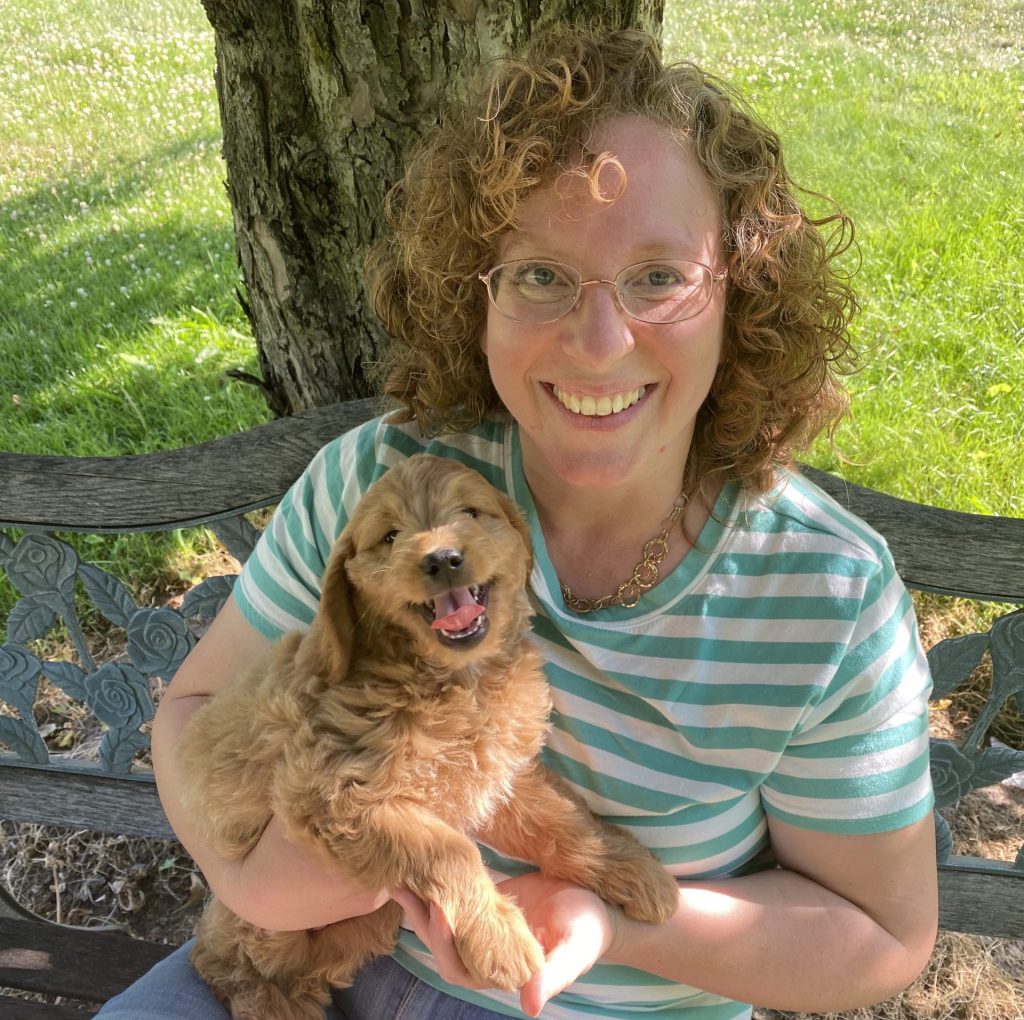 NY Dandy Doodles Amy Breeder under tree holding goldendoodle puppy